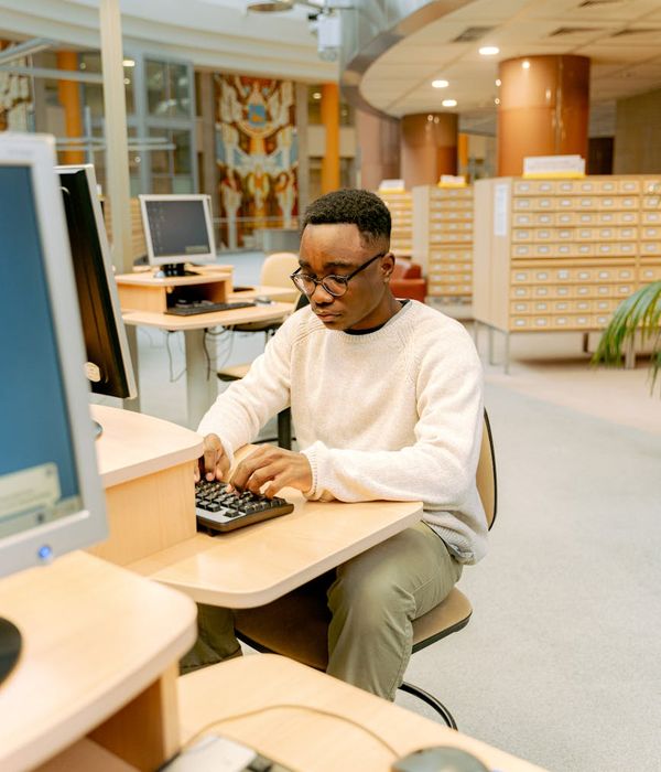 Modern office workspace with computers showing architectural design software and eco-building models